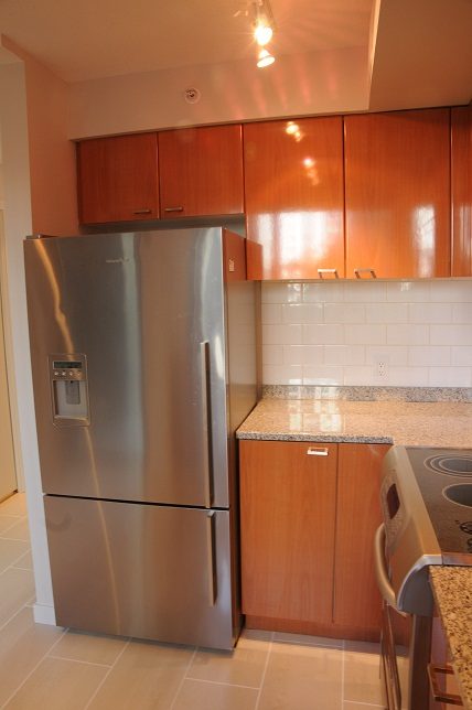 Bright kitchen with stainless steel fridge, wooden cabinets, and granite countertops. - 1275 Alberni Street, Vancouver Downtown