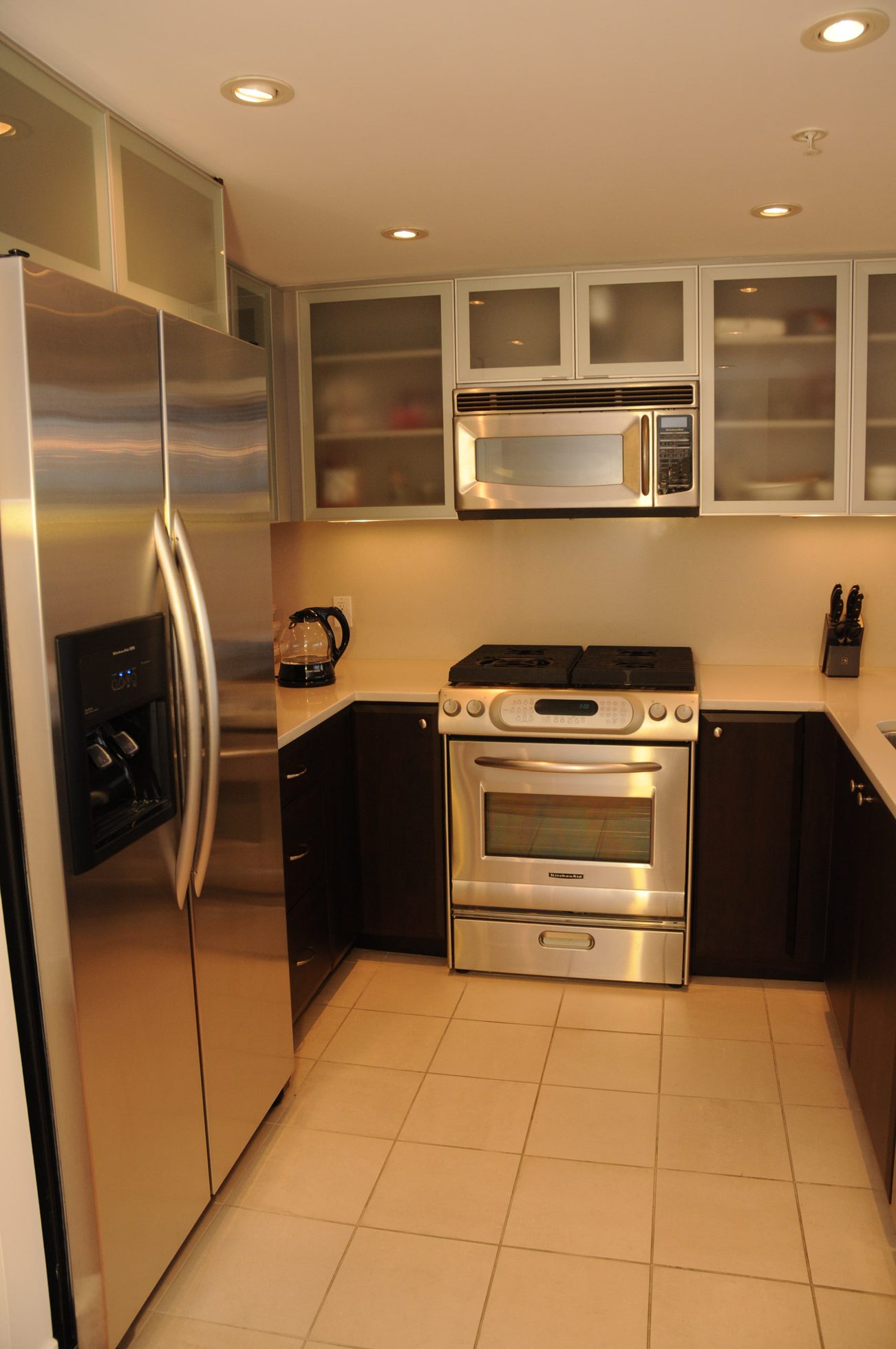 Bright kitchen with stainless steel appliances, dark cabinets, and white countertops. - 2901 - 1205 West Hastings Street, Vancouver Downtown