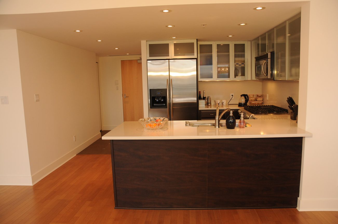 Bright kitchen with white countertops, dark wood island, and stainless steel appliances. - 2901 - 1205 West Hastings Street, Vancouver Downtown