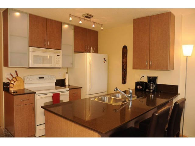 Bright kitchen with granite countertops and modern appliances, featuring a large island and wooden cabinets.