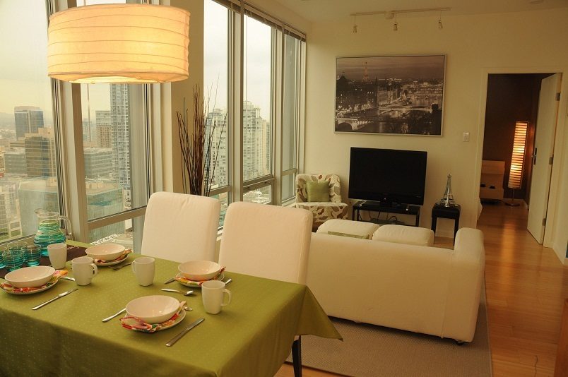 Bright dining area with city view and modern decor, featuring a green tablecloth and white chairs. - 1910 - 989 Nelson Street, Vancouver Downtown