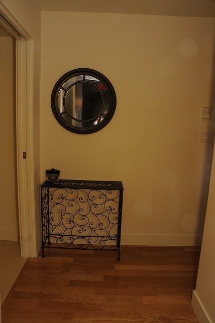 Foyer with wooden floors, black console table, and round mirror. - 1405- 565 Smithe Street, Vancouver Downtown