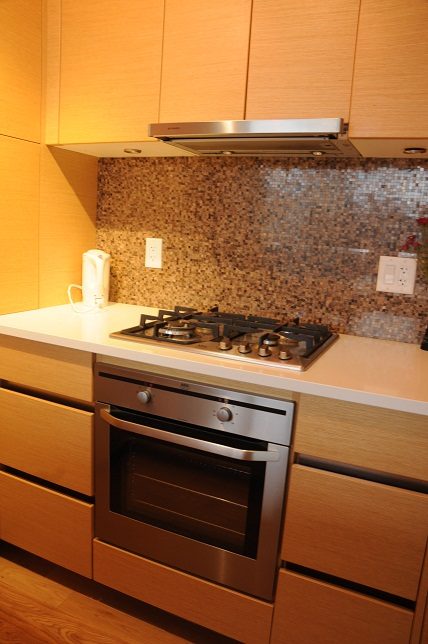 Bright kitchen with modern gas stove, mosaic backsplash, and light wood cabinets. - 1405- 565 Smithe Street, Vancouver Downtown