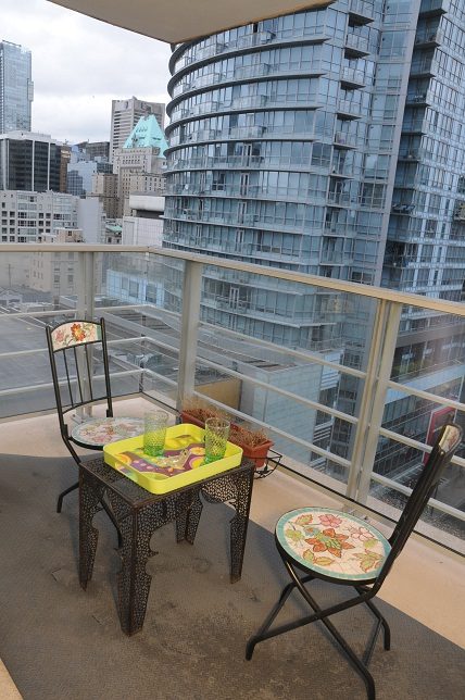 Furnished balcony with city view, patio furniture, and modern high-rise buildings in the background. - 1405- 565 Smithe Street, Vancouver Downtown