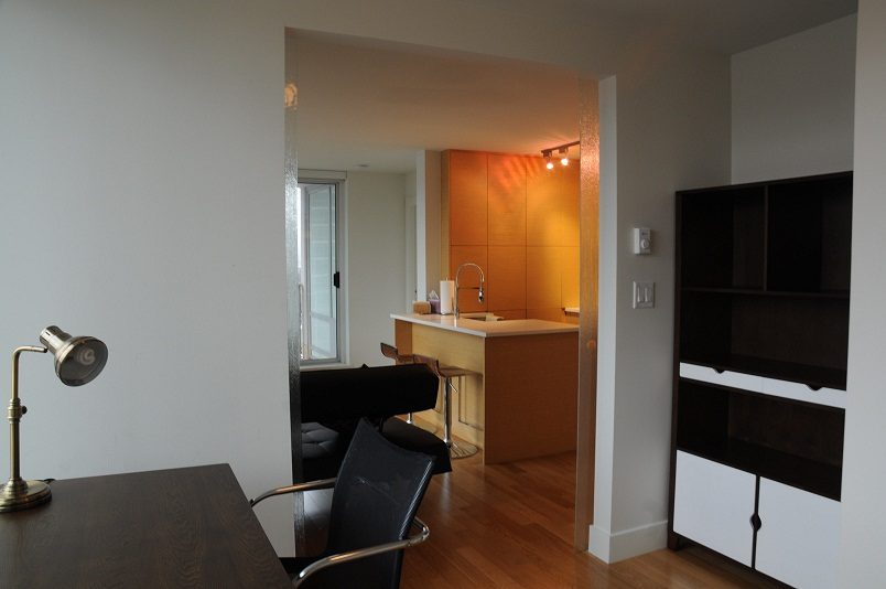Bright kitchen with wooden cabinets and modern bar stools, hardwood floors, and a city view. - 1405- 565 Smithe Street, Vancouver Downtown