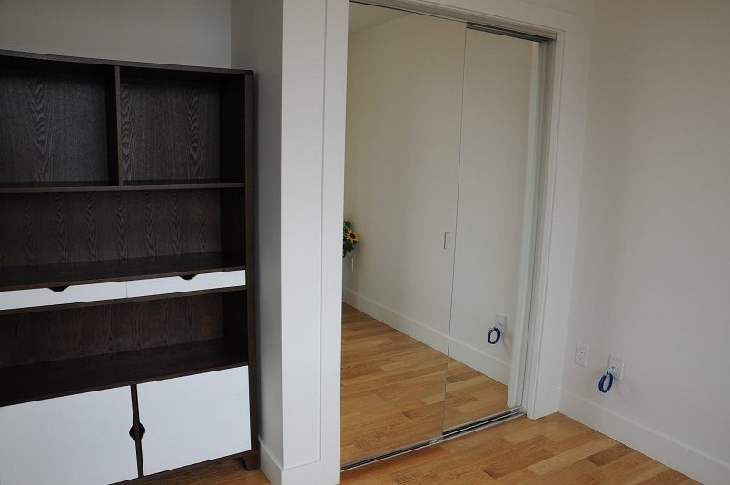 Bright living room with dark wood shelving and sliding glass door leading to another room. - 1405- 565 Smithe Street, Vancouver Downtown