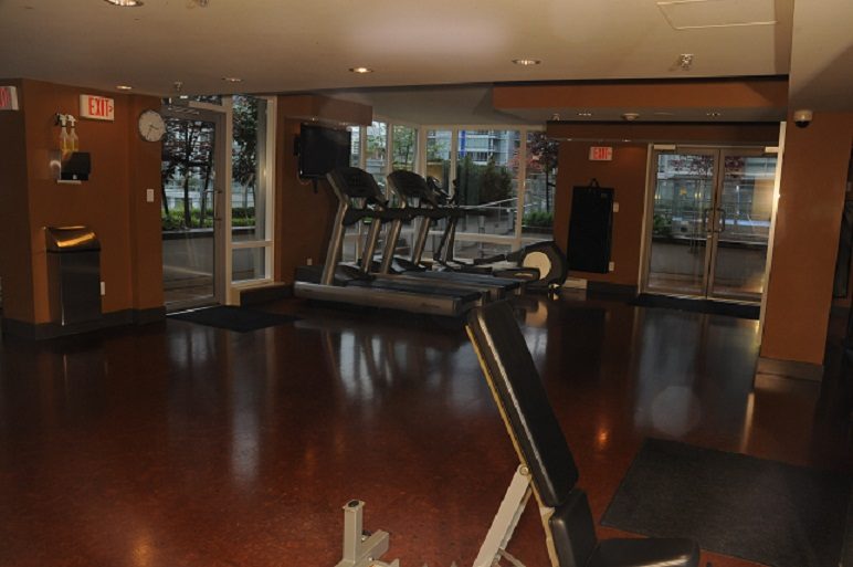 Furnished gym with cardio machines and city view windows. - 1405- 565 Smithe Street, Vancouver Downtown