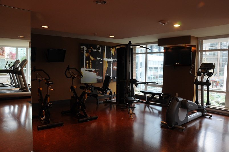 Bright fitness room with hardwood floors, exercise bikes, and city view windows. - 1405- 565 Smithe Street, Vancouver Downtown
