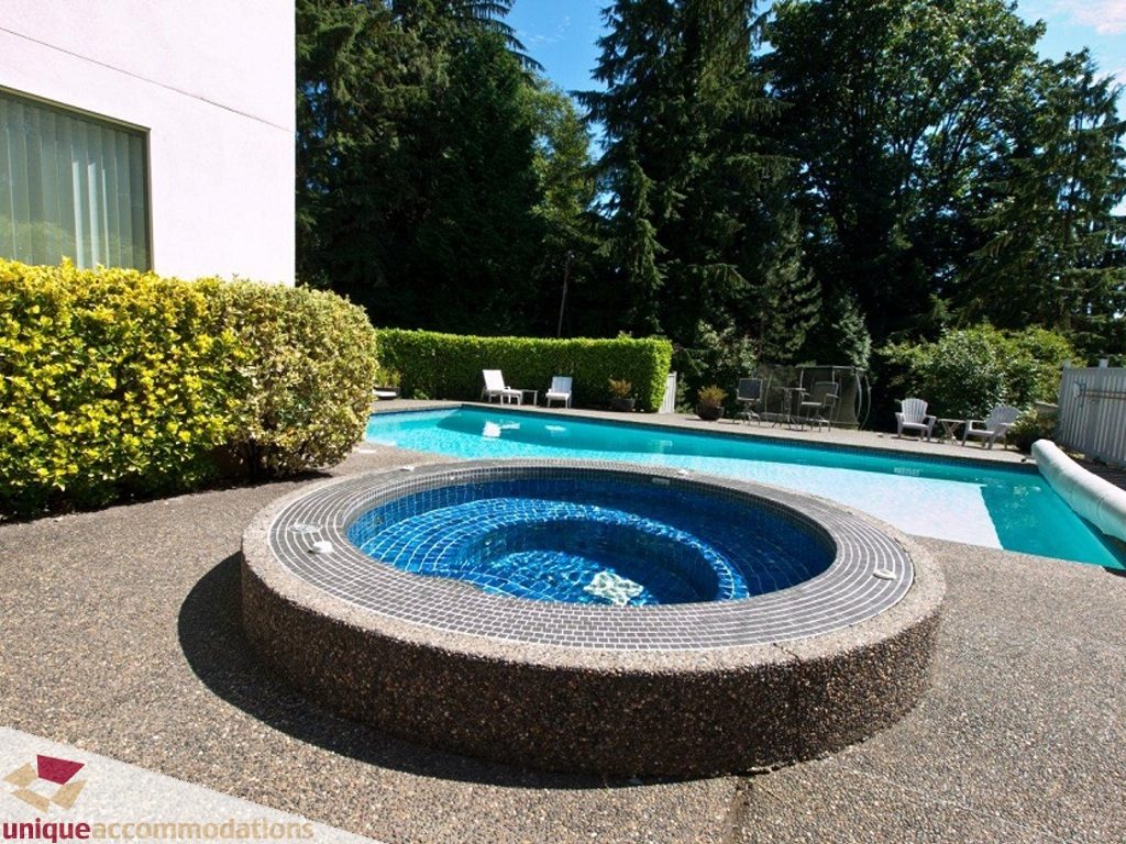 Spacious backyard with a circular hot tub and a large pool surrounded by lush greenery. - 750 Anderson Crescent, West Vancouver