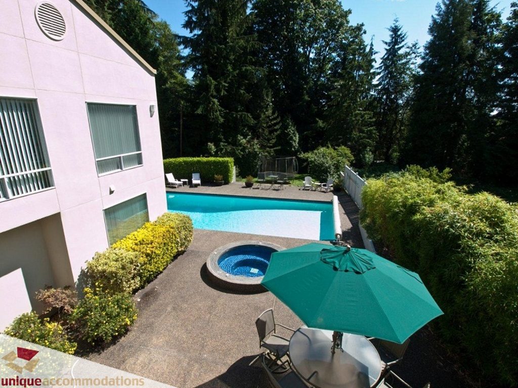 Furnished patio with umbrella, table, and hot tub, surrounded by greenery. - 750 Anderson Crescent, West Vancouver