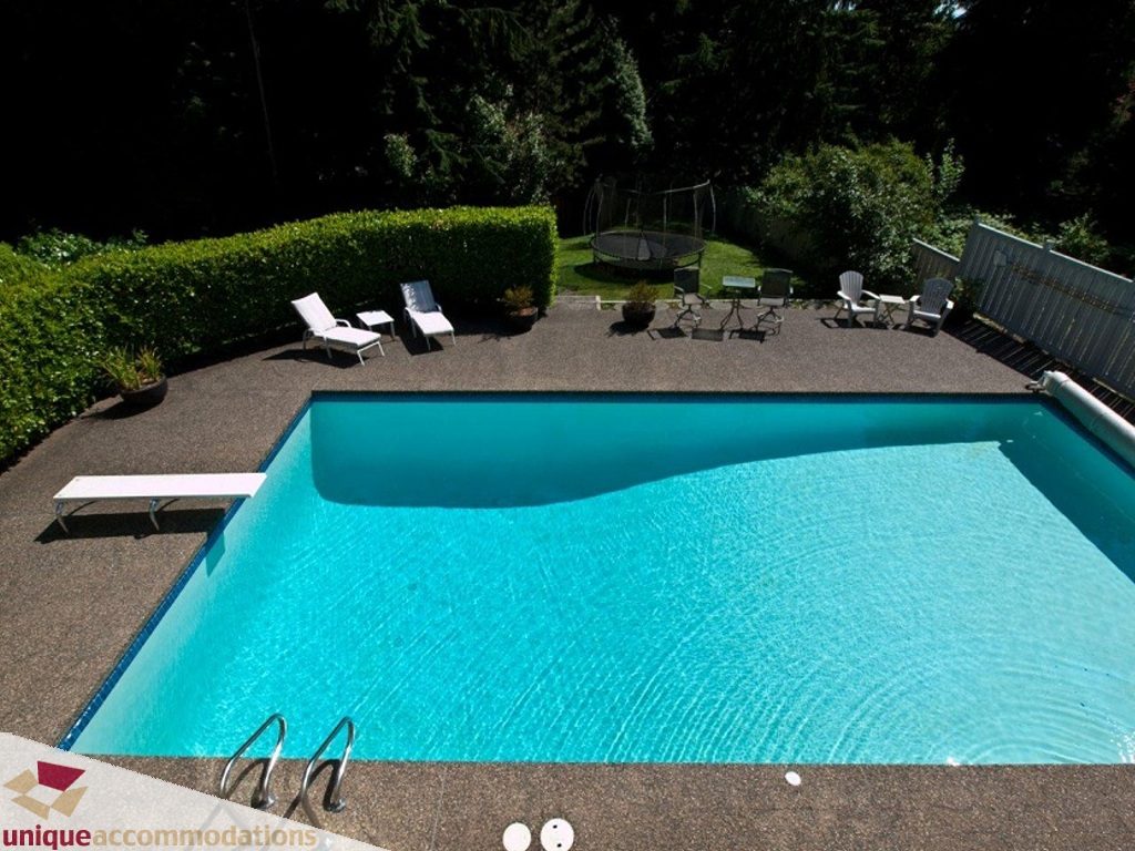 Spacious backyard with a large, clear blue pool, lounge chairs, and a trampoline. - 750 Anderson Crescent, West Vancouver