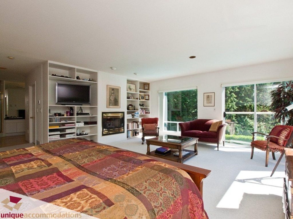 Spacious living room with large windows, cozy seating, and a vibrant patchwork bedspread. - 750 Anderson Crescent, West Vancouver
