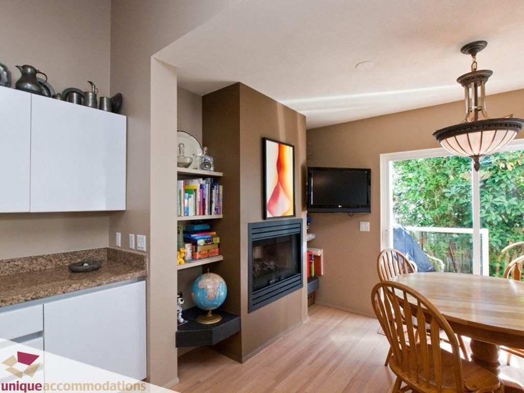 Bright kitchen with granite countertops, hardwood floors, and a cozy living area featuring a fireplace and built-in shelves.
