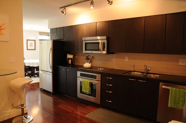 Bright kitchen with dark wood cabinets, stainless steel appliances, and hardwood floors. - 705 - 538 Smithe, Vancouver Downtown