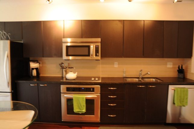 Bright kitchen with dark wood cabinets, stainless steel appliances, and granite countertops. - 705 - 538 Smithe, Vancouver Downtown