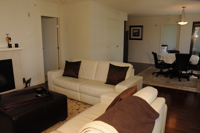 Bright living room with white leather sofa, hardwood floors, and a fireplace. - 705 - 538 Smithe, Vancouver Downtown