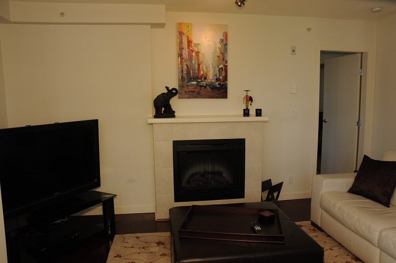 Furnished living room with a fireplace, flat-screen TV, and modern decor. - 705 - 538 Smithe, Vancouver Downtown