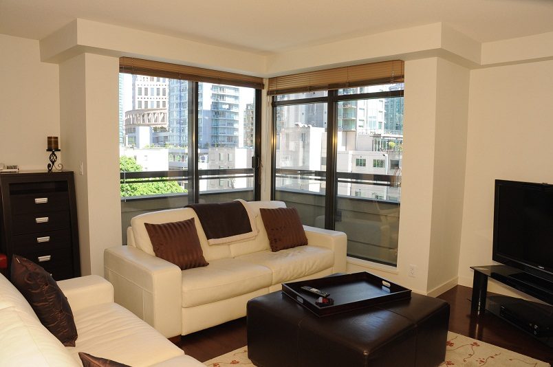 Bright living room with city view, white leather sofa, hardwood floors, and large windows. - 705 - 538 Smithe, Vancouver Downtown