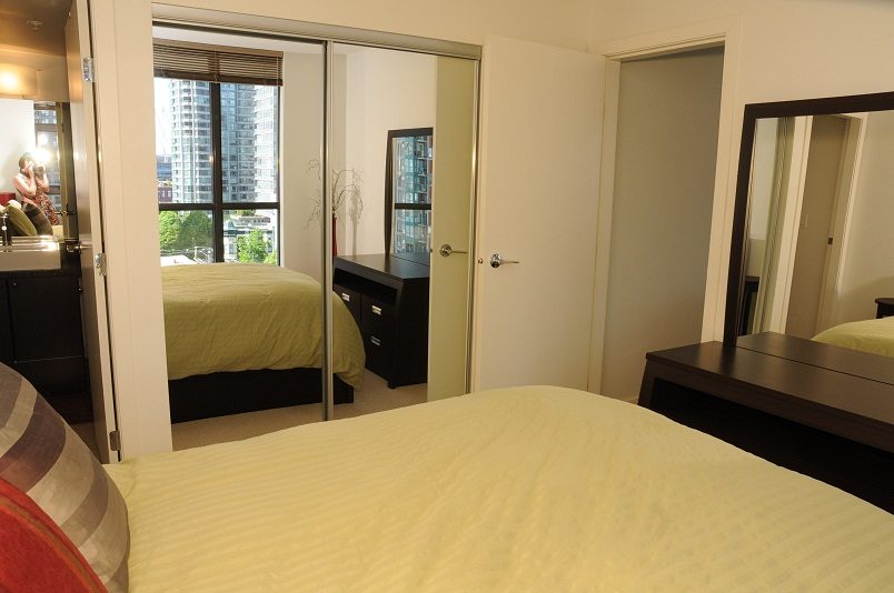 Spacious bedroom with mirrored closet doors, city view, and modern furnishings. - 705 - 538 Smithe, Vancouver Downtown