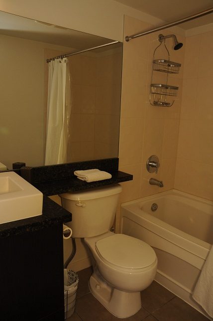 Bathroom with dark countertops, white fixtures, and a shower. - 705 - 538 Smithe, Vancouver Downtown