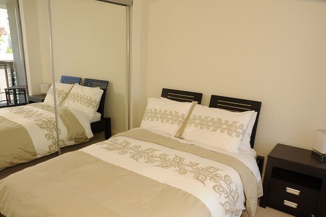 Furnished 2-bedroom condo with neatly made beds and decorative pillows. - 705 - 538 Smithe, Vancouver Downtown