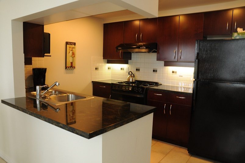 Bright kitchen with dark granite countertops and modern appliances, showcasing a sleek design. - 1607 - 1199 Marinaside Crescent, Vancouver Downtown