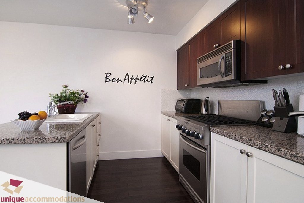 Bright kitchen with granite countertops, stainless steel appliances, and dark wood cabinets. - PH-1668 Alberni Street, Vancouver Downtown