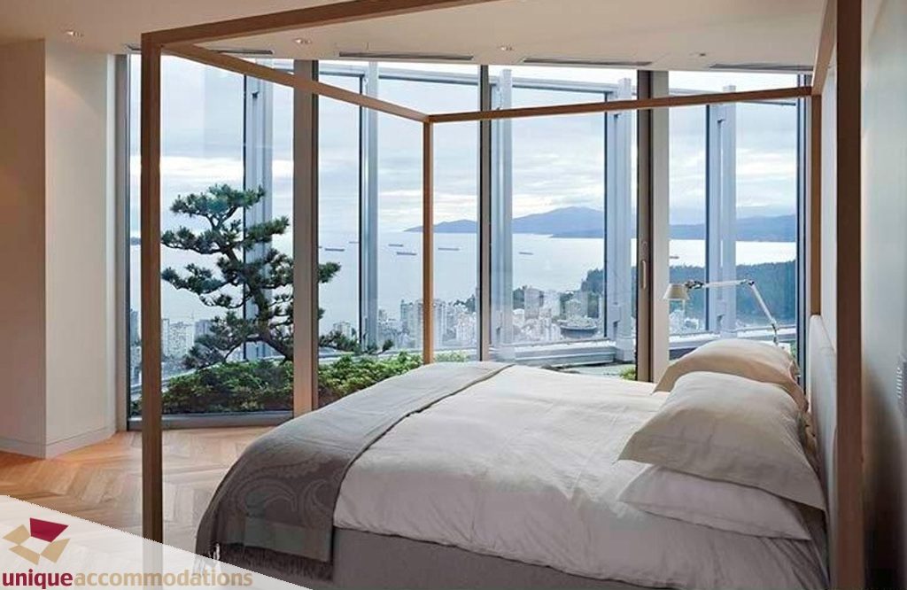 Spacious bedroom with a stunning city view and large windows, featuring a canopy bed and hardwood floors. - 6102-1128 West Georgia, Vancouver Downtown