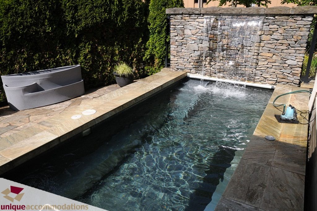 Furnished outdoor patio with stone wall fountain and spa-like water feature. - 3035 Newmarket Drive, North Vancouver