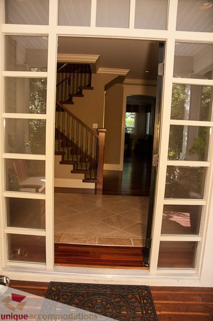 Foyer with glass doors leading to a staircase, hardwood floors, and a view into the living area. - 3035 Newmarket Drive, North Vancouver