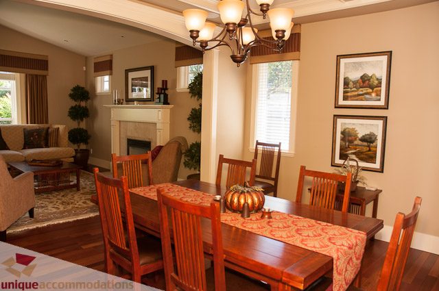 Furnished dining room with wooden chairs, red patterned tablecloths, and a chandelier. - 3035 Newmarket Drive, North Vancouver
