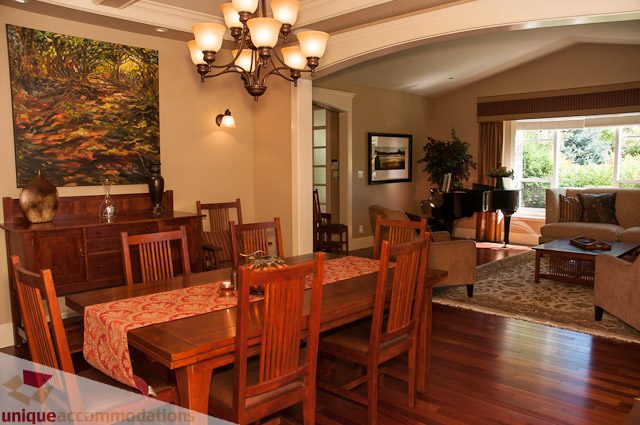 Furnished dining room with wooden chairs and a chandelier, hardwood floors, and a large window view. - 3035 Newmarket Drive, North Vancouver