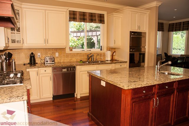 Bright kitchen with granite countertops, hardwood floors, and a view of the backyard. - 3035 Newmarket Drive, North Vancouver