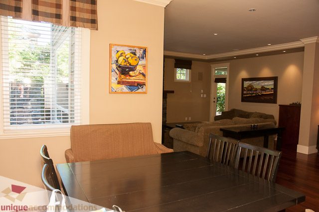 Furnished dining and living area with hardwood floors and a city view. - 3035 Newmarket Drive, North Vancouver
