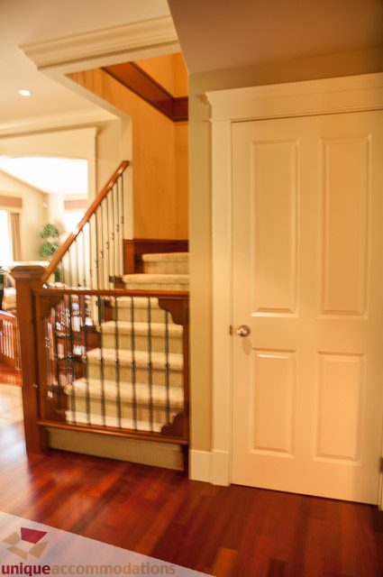 Furnished entryway with hardwood floors and a white door leading to the staircase. - 3035 Newmarket Drive, North Vancouver