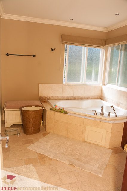 Spacious bathroom with corner tub, tiled floor, and natural light from window. - 3035 Newmarket Drive, North Vancouver