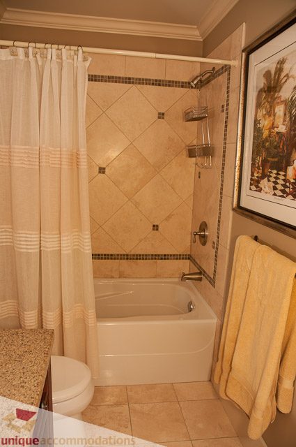 Furnished bathroom with a bathtub, tiled walls, and a shower curtain. - 3035 Newmarket Drive, North Vancouver