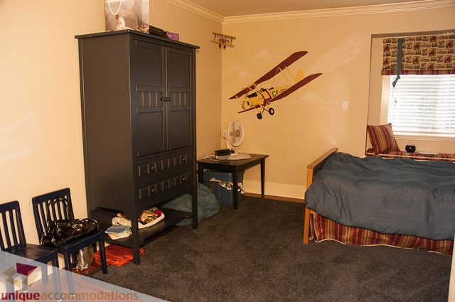 Bedroom with twin beds, a large armoire, and a wall mural of a plane. - 3035 Newmarket Drive, North Vancouver