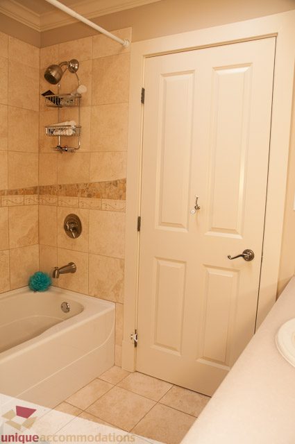 Bathroom with beige tiles, shower caddy, and bathtub. - 3035 Newmarket Drive, North Vancouver