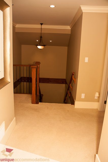 Staircase leading to upper level with wooden railings and carpeted steps. - 3035 Newmarket Drive, North Vancouver