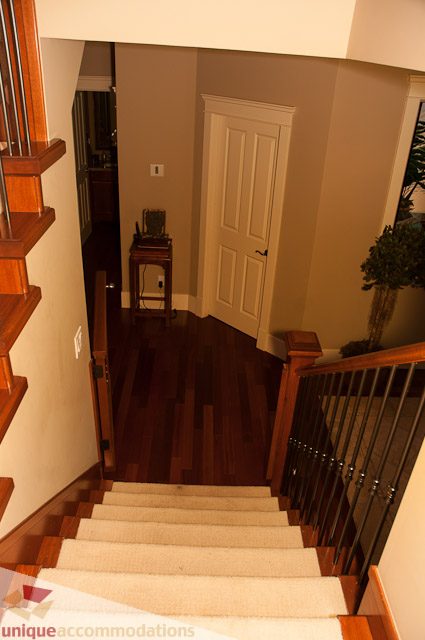 Foyer with wooden staircase, hardwood floors, and white door. - 3035 Newmarket Drive, North Vancouver