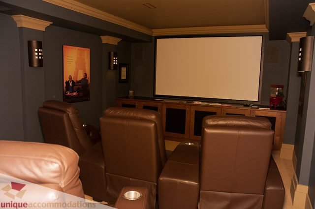Luxurious home theater with plush leather seating and a large screen. - 3035 Newmarket Drive, North Vancouver