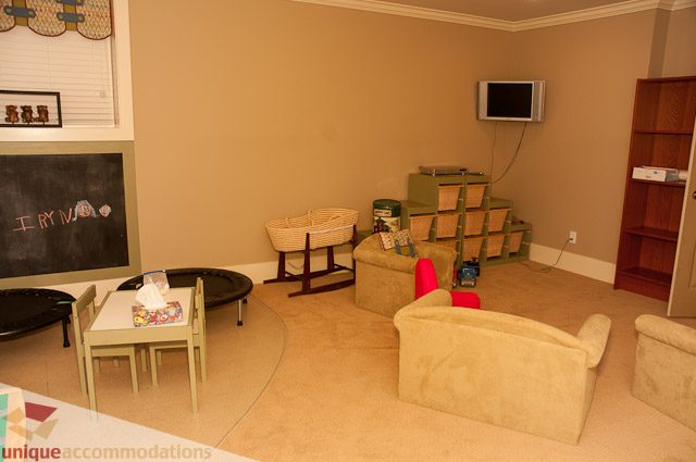 Living room with beige furniture, small TV, and storage baskets. - 3035 Newmarket Drive, North Vancouver