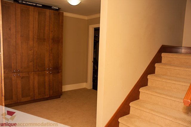 Furnished entryway leading to a spacious den with wooden cabinets and carpeted stairs. - 3035 Newmarket Drive, North Vancouver