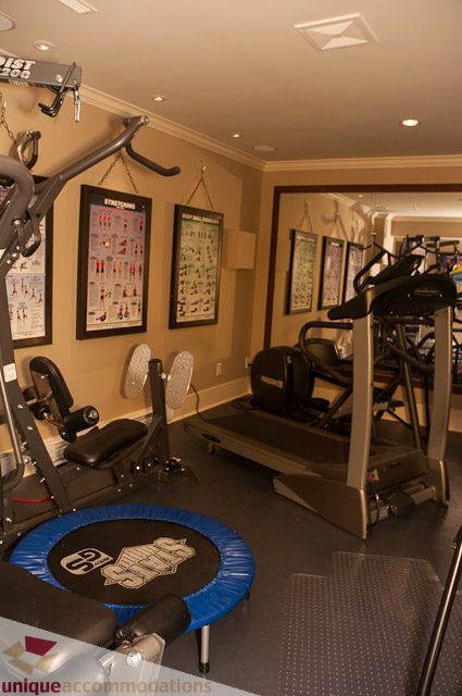 Fitness room with cardio machines and exercise posters. - 3035 Newmarket Drive, North Vancouver