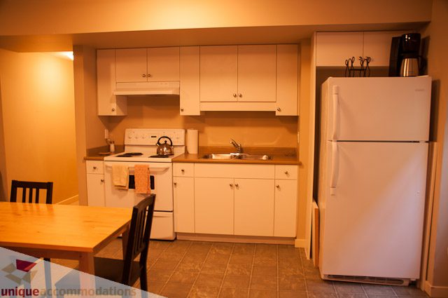 Bright kitchen with white cabinets, tiled floor, and stainless steel appliances. - 3035 Newmarket Drive, North Vancouver
