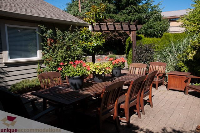 Furnished patio with wooden furniture and blooming flowers. - 3035 Newmarket Drive, North Vancouver