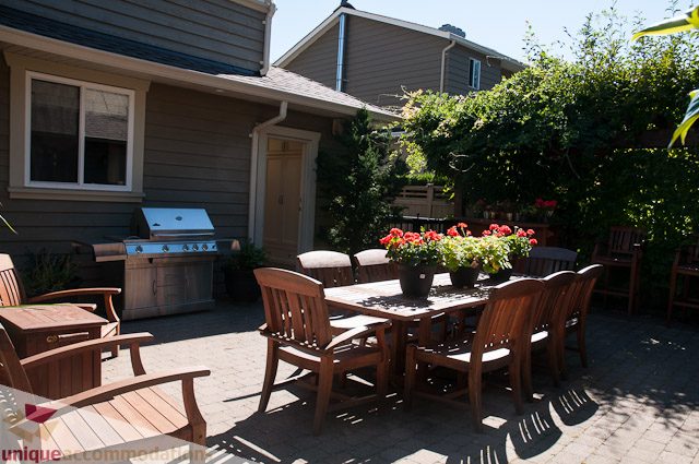 Furnished patio with wooden furniture, outdoor grill, and potted flowers. - 3035 Newmarket Drive, North Vancouver