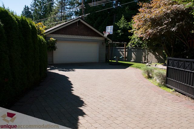 Fenced backyard with brick patio and lush greenery. - 3035 Newmarket Drive, North Vancouver