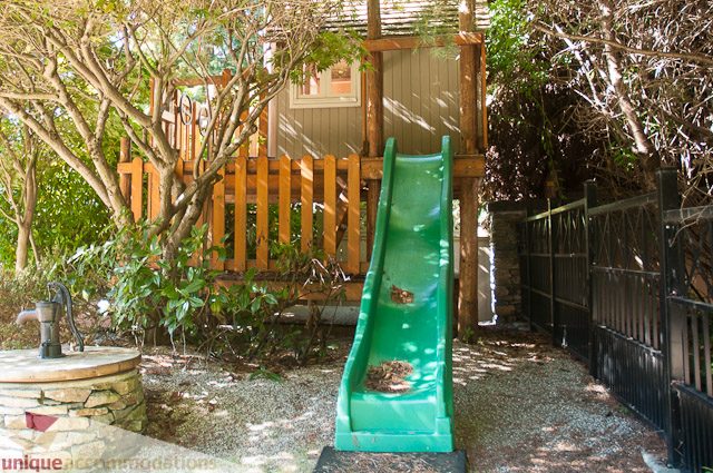 Bright outdoor play area with a green slide and wooden fence. - 3035 Newmarket Drive, North Vancouver